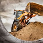Radlader mit Anbaugerät auf Baustelle – Koppelhaken sorgt für sichere Befestigung der Frontschaufel