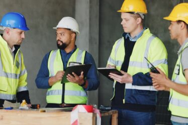 Baubesprechung mit Sicherheitshelmen und Westen | Absperrung Baustelle